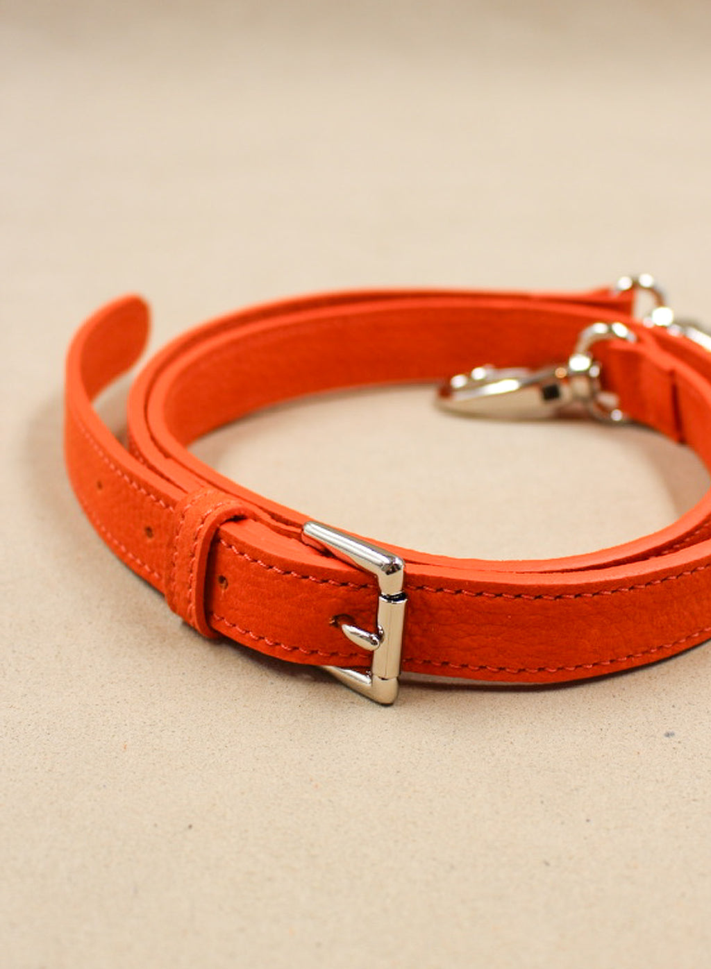 Bandoulière en cuir nubuck orange, enroulée